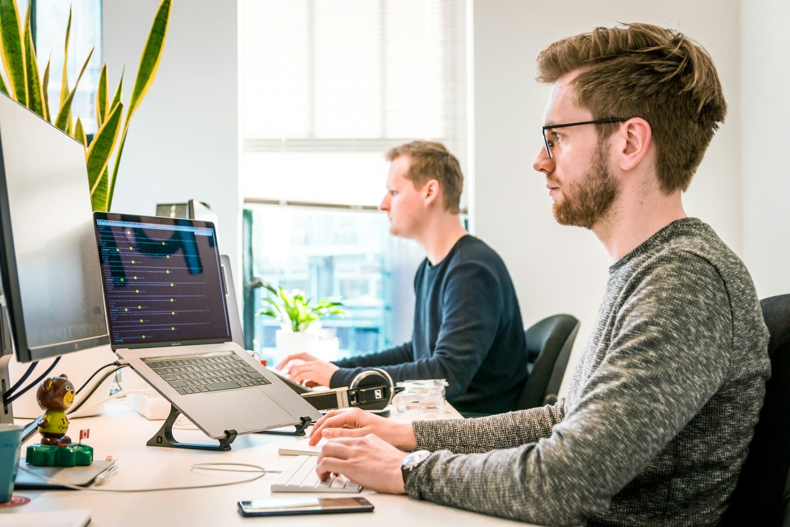 Two IT specialists working together at their monitors